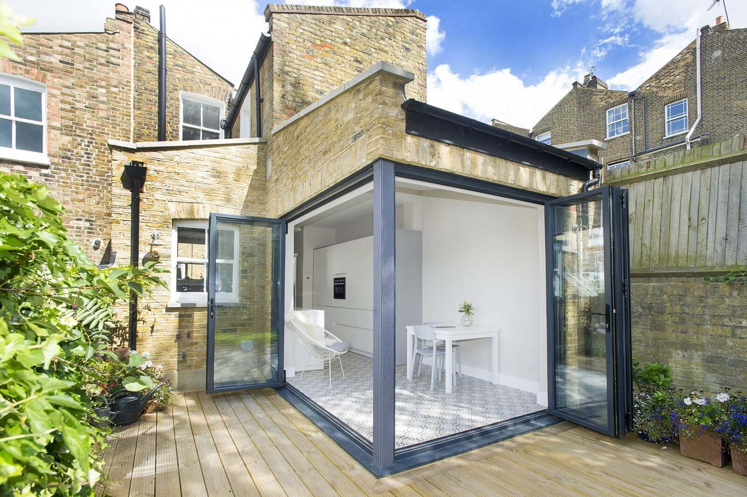 Flat-roof rear extension on a London brick terrace with bifold doors opening onto a timber deck, a Build Team project