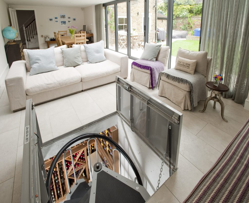 Living area with a glass hatch in the floor opening onto a spiral wine cellar, Klea Avenue SW4