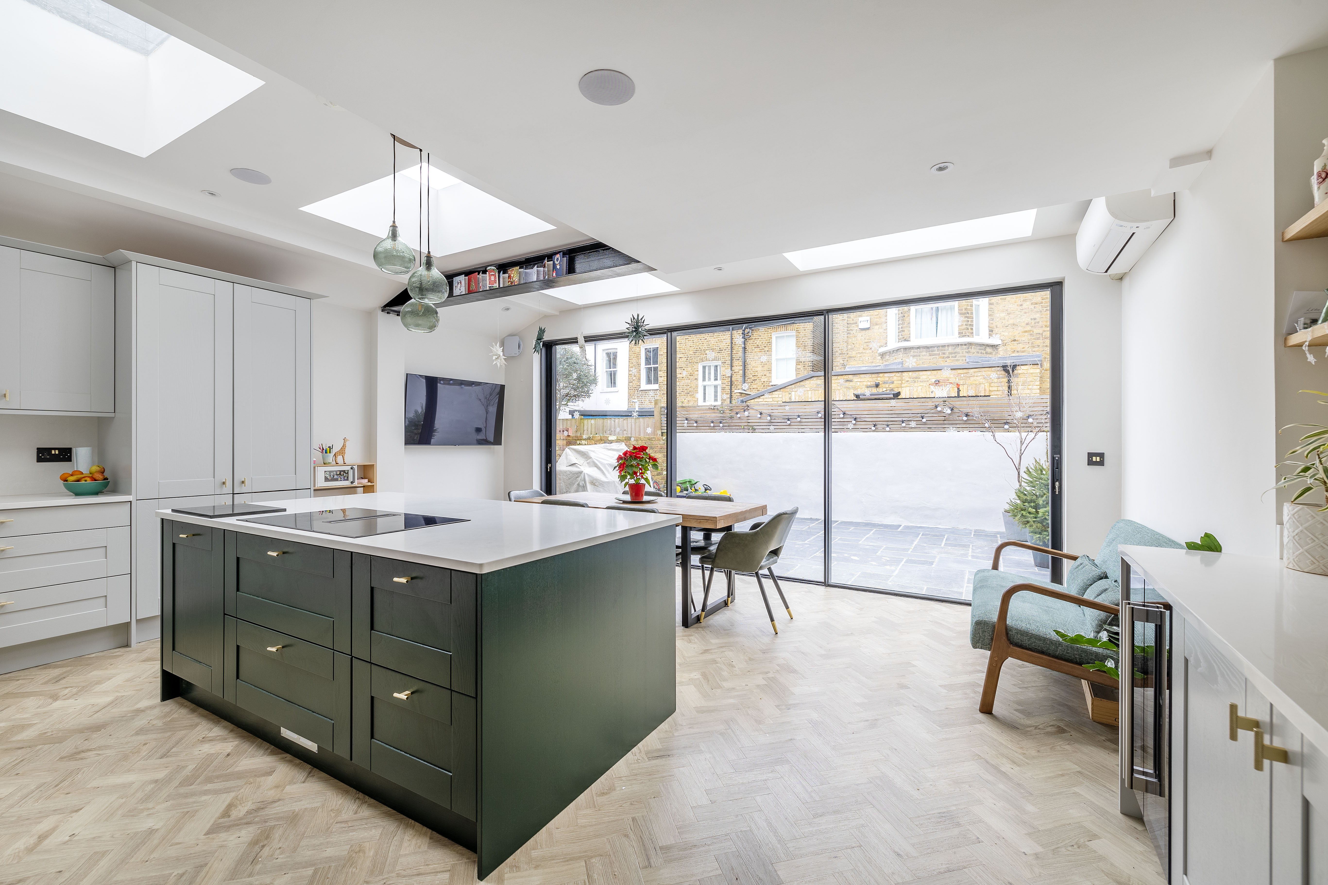 Open-plan kitchen with dark green island, parquet floor and skylights, side return extension East Dulwich SE22